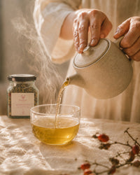 Pouring Mother's Recovery tea — steaming postpartum herbal infusion