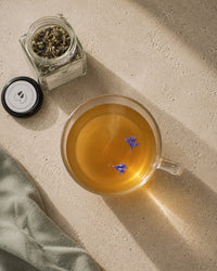 Nurture and Nourish tea brewed — amber lactation support infusion with cornflower petals