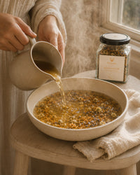 Pouring Soothe and Restore herbal infusion into a steaming basin for postpartum rinsing